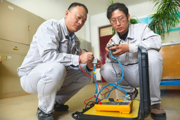 圖為配電班QC小組成員對自主研制的試驗輔助裝置進(jìn)行調(diào)試.jpg